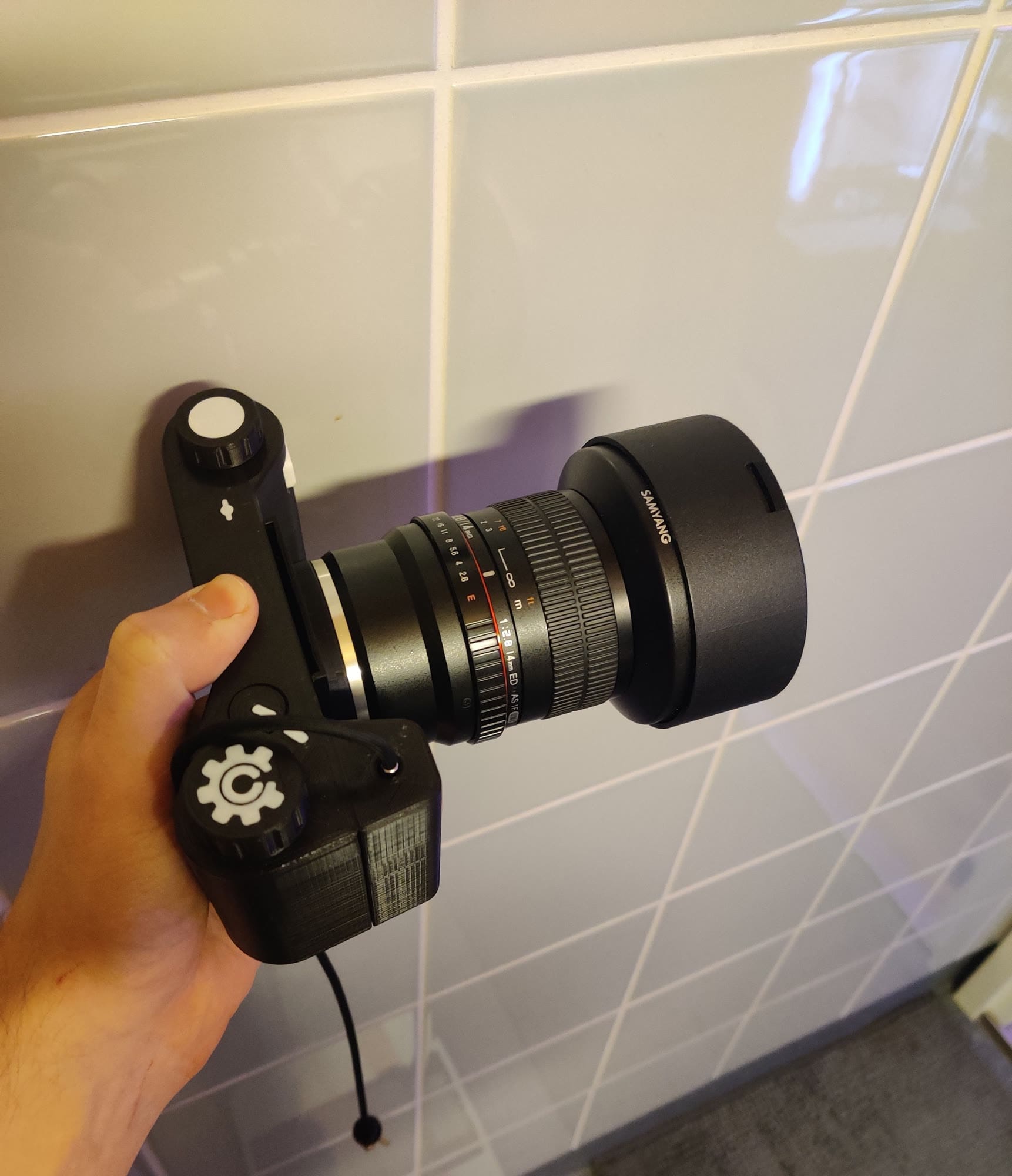 The camera held in one hand with a Samyang lens on its Sony E-mount adapter